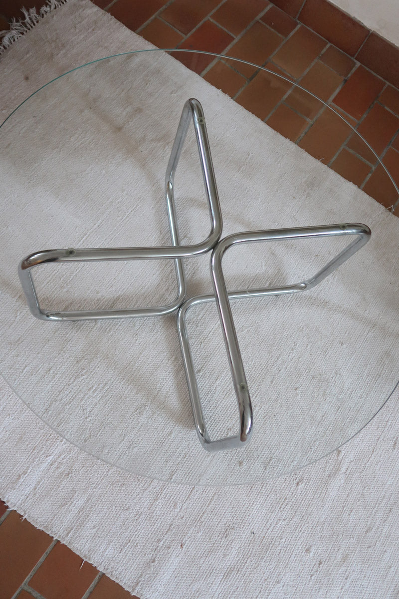 Table basse ronde des années 70 avec plateau en verre et base en tubes chromés en croix.