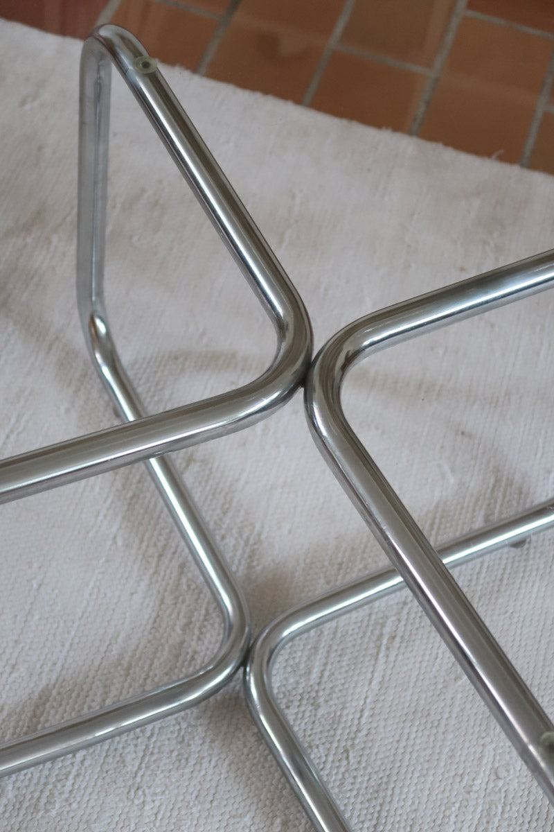 Table basse ronde des années 70 avec plateau en verre et base en tubes chromés en croix.