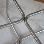 Table basse ronde des années 70 avec plateau en verre et base en tubes chromés en croix.