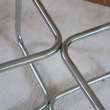 Table basse ronde des années 70 avec plateau en verre et base en tubes chromés en croix.