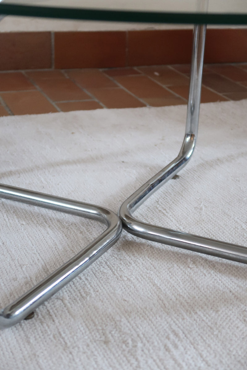 Table basse ronde des années 70 avec plateau en verre et base en tubes chromés en croix.