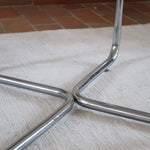 Table basse ronde des années 70 avec plateau en verre et base en tubes chromés en croix.