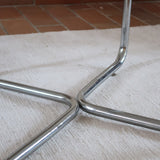 Table basse ronde des années 70 avec plateau en verre et base en tubes chromés en croix.