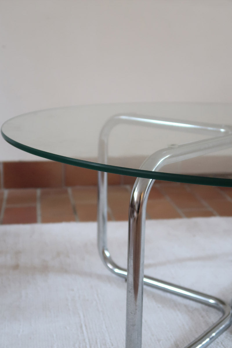 Table basse ronde des années 70 avec plateau en verre et base en tubes chromés en croix.