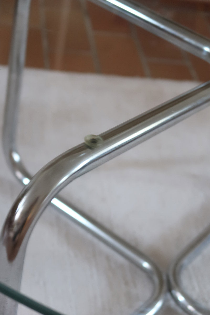 Table basse ronde des années 70 avec plateau en verre et base en tubes chromés en croix.