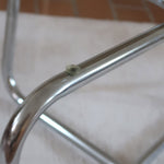 Table basse ronde des années 70 avec plateau en verre et base en tubes chromés en croix.