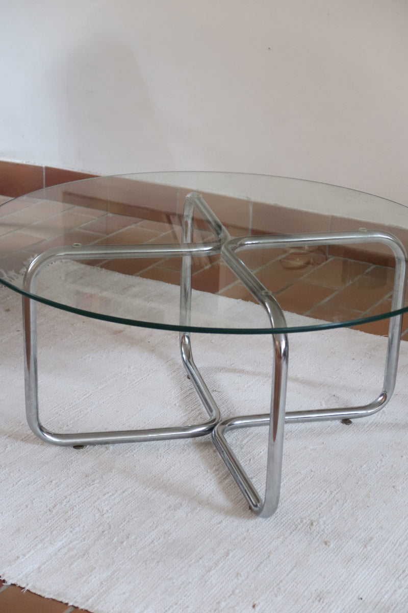 Table basse ronde des années 70 avec plateau en verre et base en tubes chromés en croix.