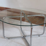 Table basse ronde des années 70 avec plateau en verre et base en tubes chromés en croix.