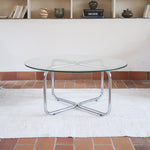 Table basse ronde des années 70 avec plateau en verre et base en tubes chromés en croix.