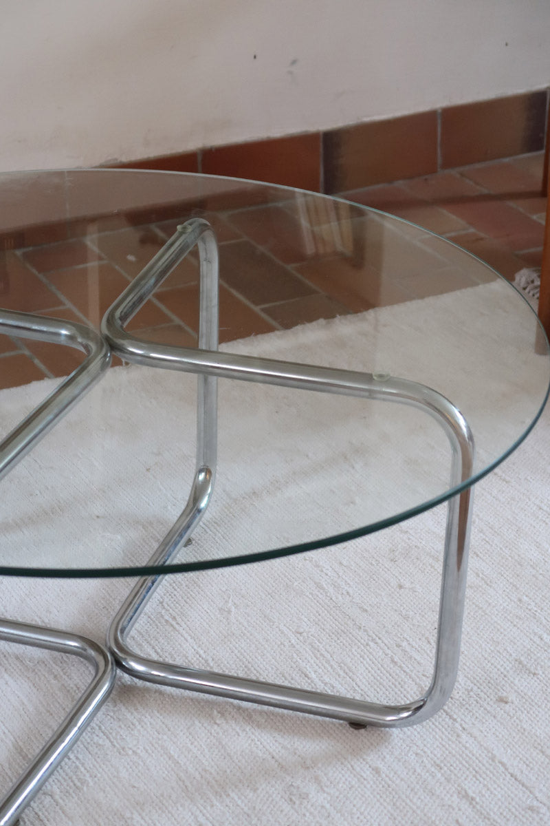 Table basse ronde des années 70 avec plateau en verre et base en tubes chromés en croix.
