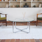 Table basse ronde des années 70 avec plateau en verre et base en tubes chromés en croix.