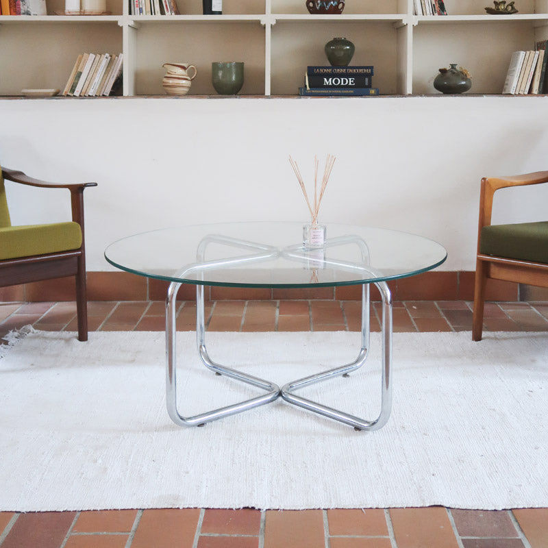 Table basse ronde des années 70 avec plateau en verre et base en tubes chromés en croix.
