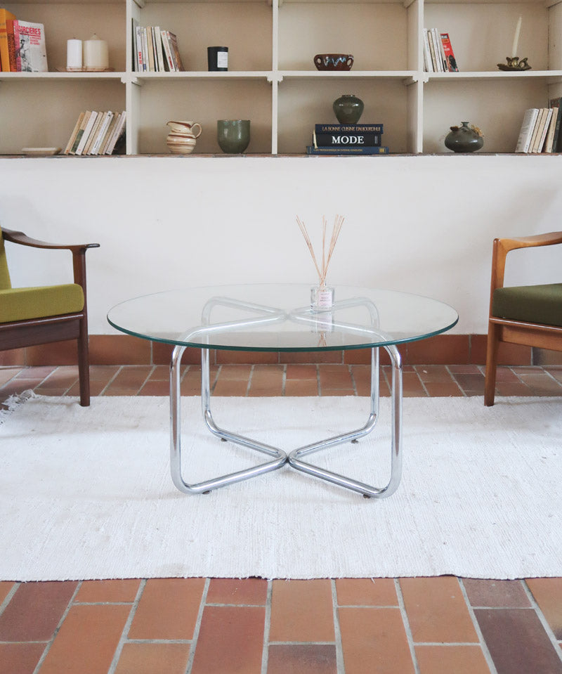 Table basse ronde des années 70 avec plateau en verre et base en tubes chromés en croix.