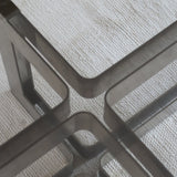 Table basse vintage en verre fumé, années 70, grand plateau rectangulaire à angles arrondis, piétement en inox brossé composé de deux cadres en U réunis par une croix centrale
