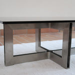 Table basse vintage en verre fumé, années 70, grand plateau rectangulaire à angles arrondis, piétement en inox brossé composé de deux cadres en U réunis par une croix centrale