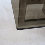 Table basse vintage en verre fumé, années 70, grand plateau rectangulaire à angles arrondis, piétement en inox brossé composé de deux cadres en U réunis par une croix centrale