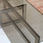 Table basse vintage en verre fumé, années 70, grand plateau rectangulaire à angles arrondis, piétement en inox brossé composé de deux cadres en U réunis par une croix centrale