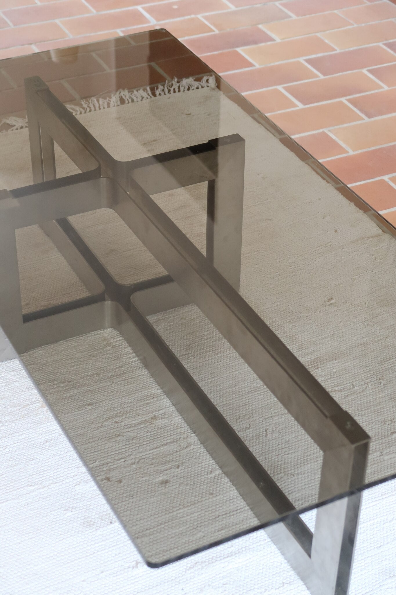 Table basse vintage en verre fumé, années 70, grand plateau rectangulaire à angles arrondis, piétement en inox brossé composé de deux cadres en U réunis par une croix centrale