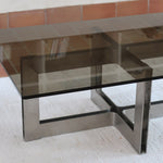 Table basse vintage en verre fumé, années 70, grand plateau rectangulaire à angles arrondis, piétement en inox brossé composé de deux cadres en U réunis par une croix centrale