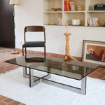 Table basse vintage en verre fumé, années 70, grand plateau rectangulaire à angles arrondis, piétement en inox brossé composé de deux cadres en U réunis par une croix centrale
