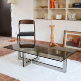 Table basse vintage en verre fumé, années 70, grand plateau rectangulaire à angles arrondis, piétement en inox brossé composé de deux cadres en U réunis par une croix centrale