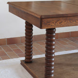 Table à manger vintage en chêne massif, pieds tournés à bobines, socle plein, plateau ouvrant central, art déco rustique esprit Charles Dudouyt
