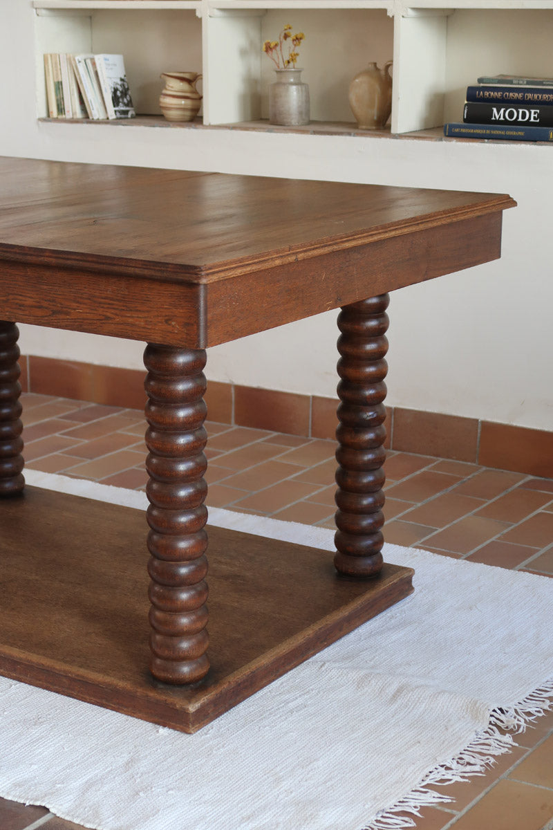 Table à manger vintage en chêne massif, pieds tournés à bobines, socle plein, plateau ouvrant central, art déco rustique esprit Charles Dudouyt