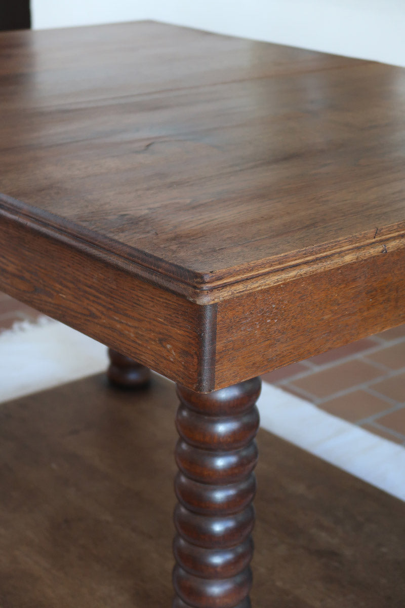 Table à manger vintage en chêne massif, pieds tournés à bobines, socle plein, plateau ouvrant central, art déco rustique esprit Charles Dudouyt