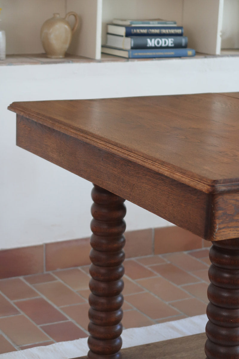 Table à manger vintage en chêne massif, pieds tournés à bobines, socle plein, plateau ouvrant central, art déco rustique esprit Charles Dudouyt