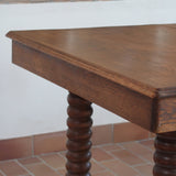Table à manger vintage en chêne massif, pieds tournés à bobines, socle plein, plateau ouvrant central, art déco rustique esprit Charles Dudouyt