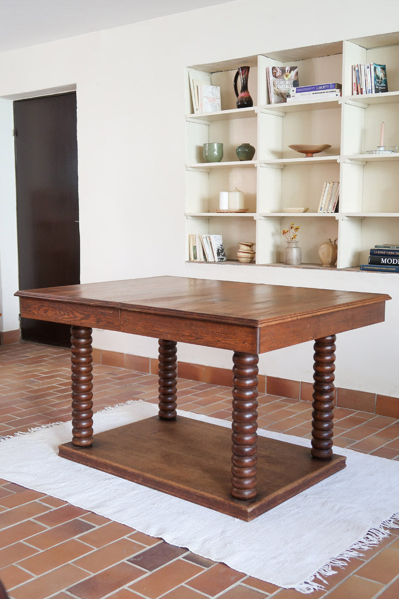 Table à manger vintage en chêne massif, pieds tournés à bobines, socle plein, plateau ouvrant central, art déco rustique esprit Charles Dudouyt