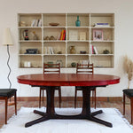 Table à manger ovale en teck avec piètement central sculptural en bois foncé et plateau à teinte rougeâtre, style scandinave vintage, présentée seule et en mise en situation.