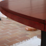 Table à manger ovale en teck avec piètement central sculptural en bois foncé et plateau à teinte rougeâtre, style scandinave vintage, présentée seule et en mise en situation.