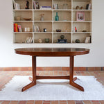 Table à manger ovale en teck avec deux rallonges intégrées, design scandinave des années 60, piètement central en bois.