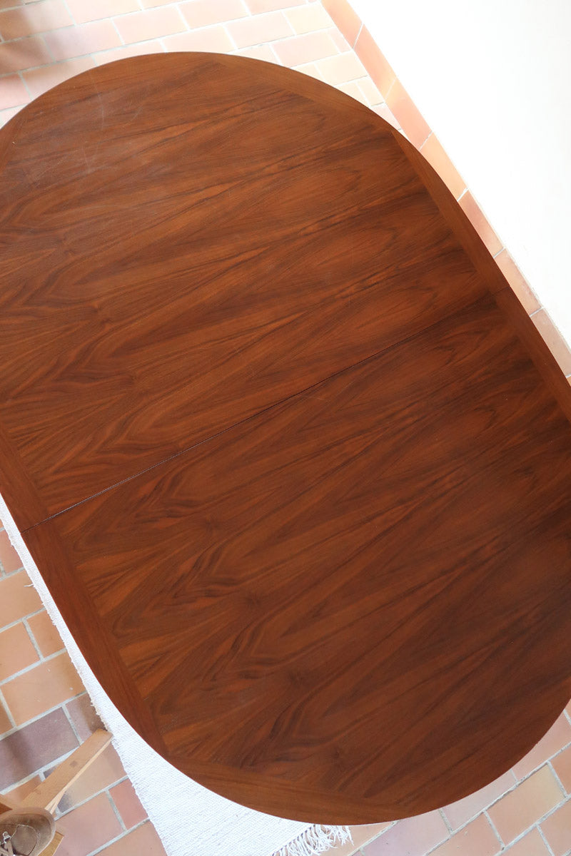 Table à manger ovale en teck avec deux rallonges intégrées, design scandinave des années 60, piètement central en bois.