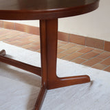 Table à manger ovale en teck avec deux rallonges intégrées, design scandinave des années 60, piètement central en bois.