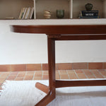 Table à manger ovale en teck avec deux rallonges intégrées, design scandinave des années 60, piètement central en bois.