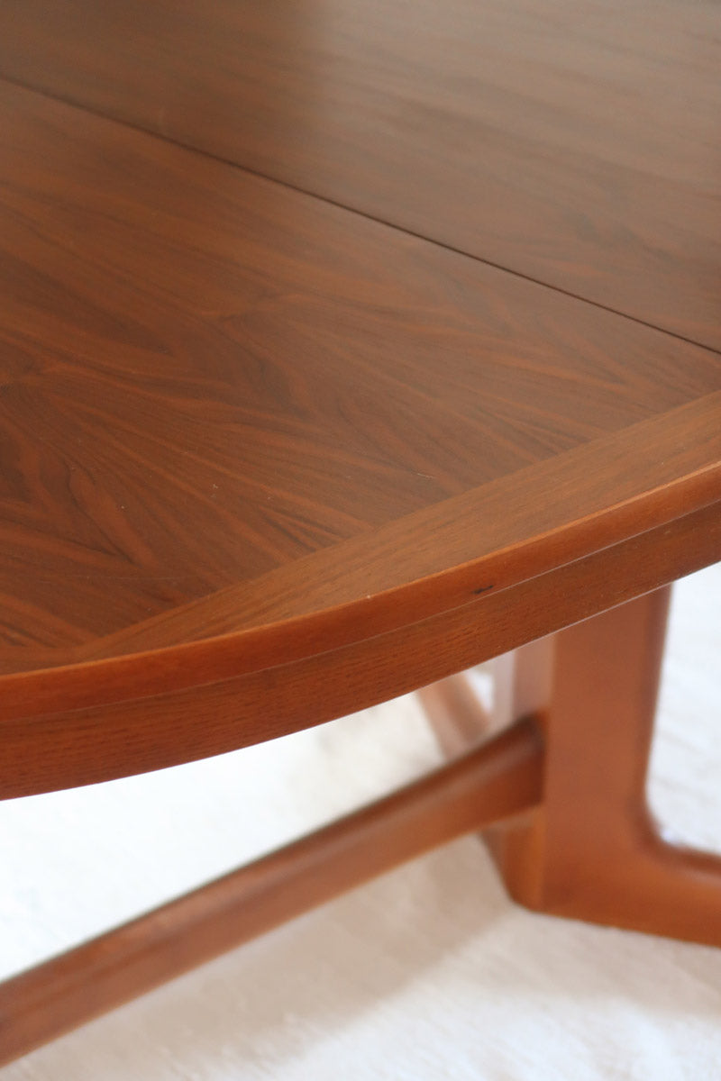 Table à manger ovale en teck avec deux rallonges intégrées, design scandinave des années 60, piètement central en bois.