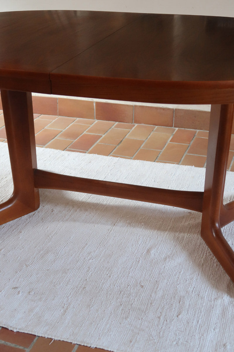 Table à manger ovale en teck avec deux rallonges intégrées, design scandinave des années 60, piètement central en bois.