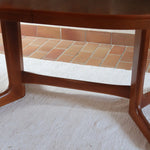 Table à manger ovale en teck avec deux rallonges intégrées, design scandinave des années 60, piètement central en bois.