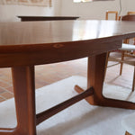 Table à manger ovale en teck avec deux rallonges intégrées, design scandinave des années 60, piètement central en bois.