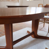 Table à manger ovale en teck avec deux rallonges intégrées, design scandinave des années 60, piètement central en bois.