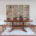 Table à manger ovale en teck avec deux rallonges intégrées, design scandinave des années 60, piètement central en bois.