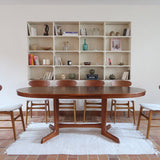 Table à manger ovale en teck avec deux rallonges intégrées, design scandinave des années 60, piètement central en bois.