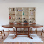 Table à manger ovale en teck avec deux rallonges intégrées, design scandinave des années 60, piètement central en bois.