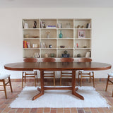 Table à manger ovale en teck avec deux rallonges intégrées, design scandinave des années 60, piètement central en bois.