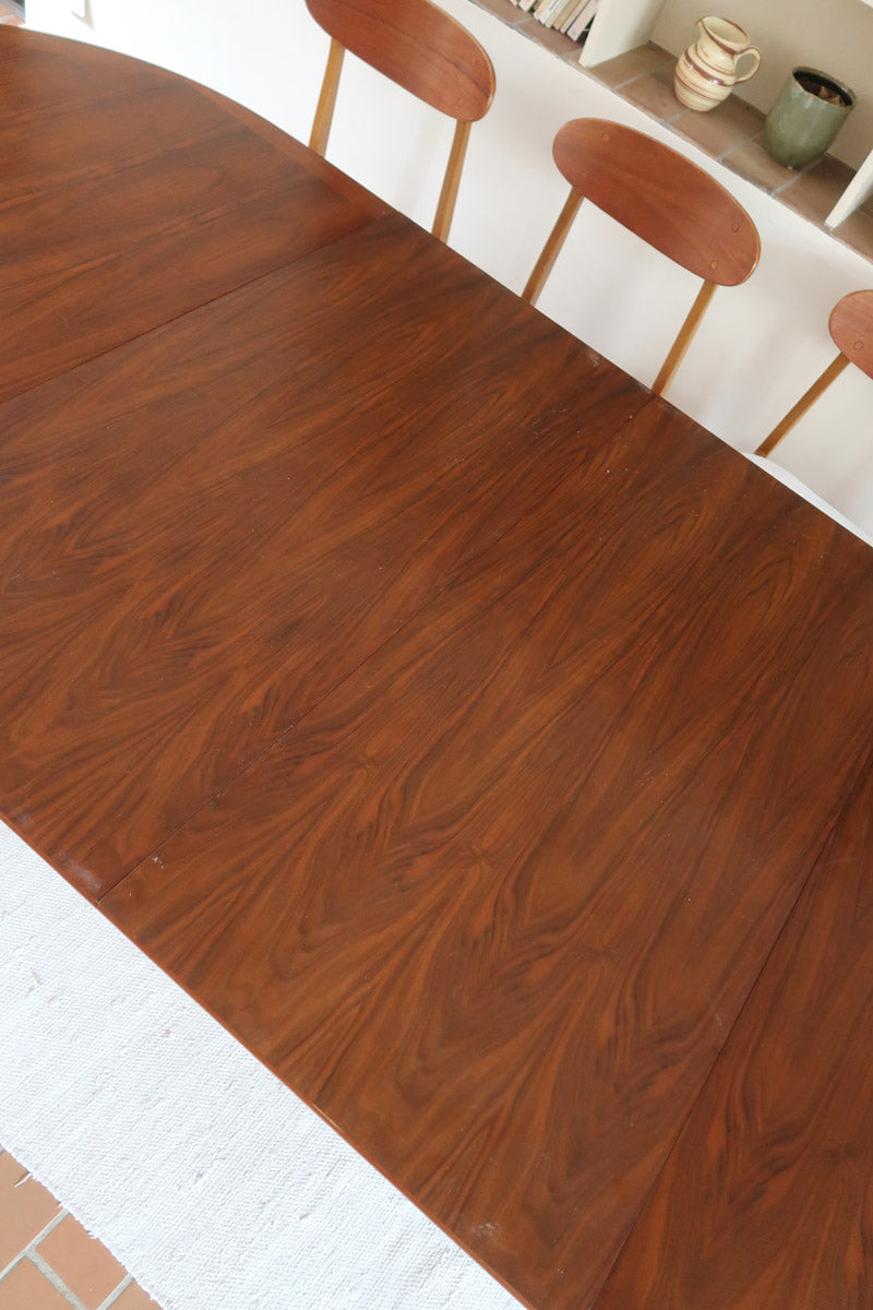 Table à manger ovale en teck avec deux rallonges intégrées, design scandinave des années 60, piètement central en bois.