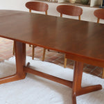 Table à manger ovale en teck avec deux rallonges intégrées, design scandinave des années 60, piètement central en bois.