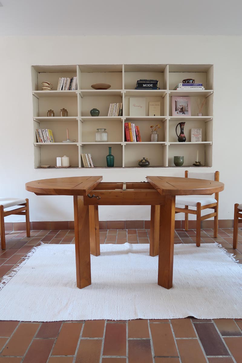 Table ronde extensible en orme massif attribuée à Maison Regain, années 80, plateau à motifs géométriques, rallonge intégrée, patine naturelle.