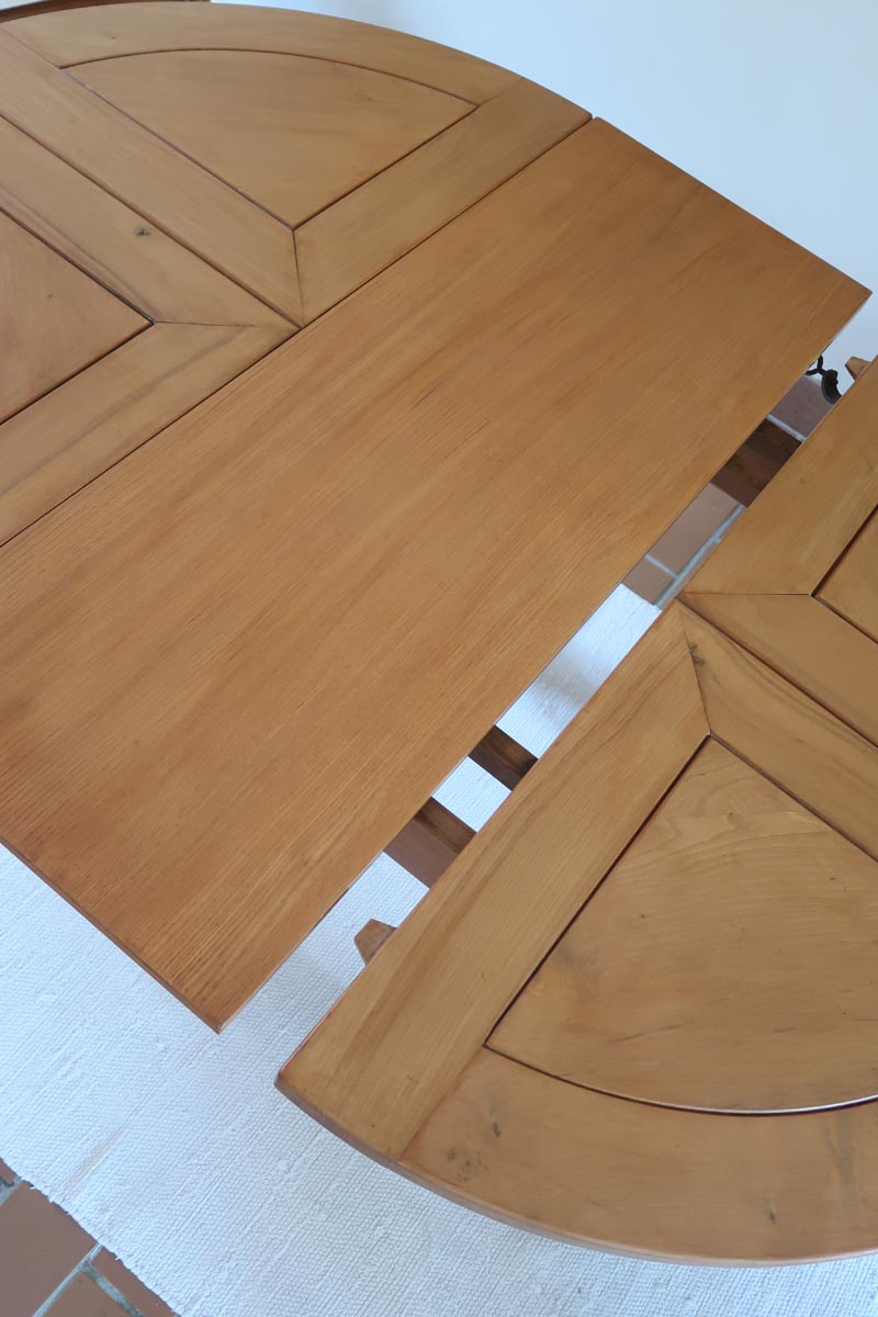 Table ronde extensible en orme massif attribuée à Maison Regain, années 80, plateau à motifs géométriques, rallonge intégrée, patine naturelle.